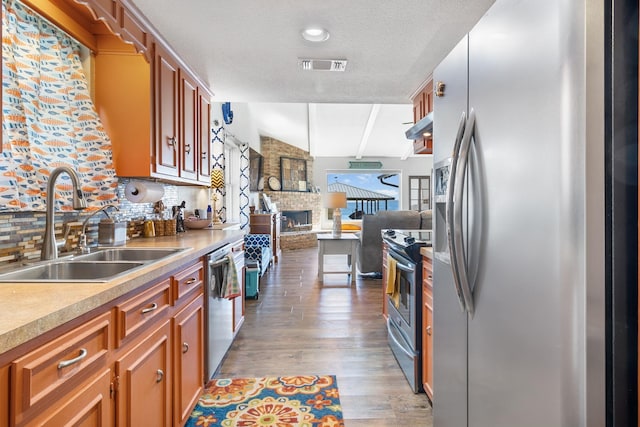 246 Indian Falls Ln, Livingston, TX 77351 - kitchen with stainless steel appliances, a sink, wood finished floors, a large fireplace, and light countertops