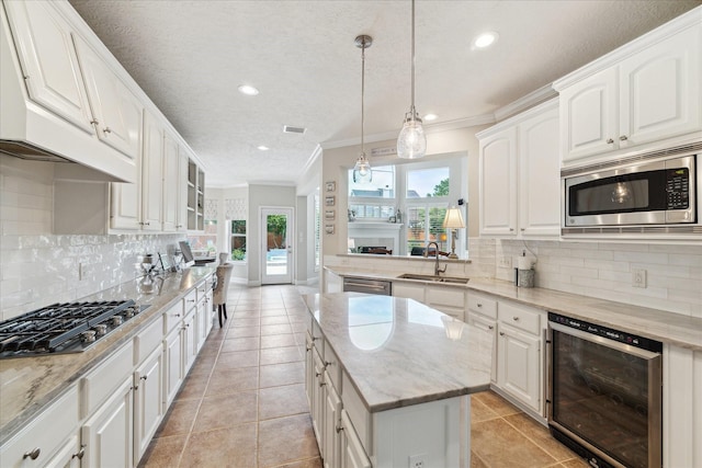 2122 Misty River Trl, Kingwood, TX 77345 - kitchen featuring beverage cooler, appliances with stainless steel finishes, a sink, crown molding, and tasteful backsplash