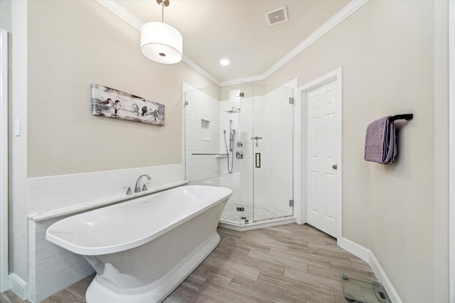 2122 Misty River Trl, Kingwood, TX 77345 - bathroom with crown molding, a freestanding bath, a stall shower, wood finished floors, and tile walls