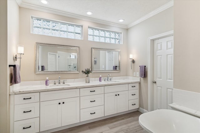 2122 Misty River Trl, Kingwood, TX 77345 - full bathroom featuring double vanity, ornamental molding, a freestanding tub, a shower with shower door, and wood finished floors