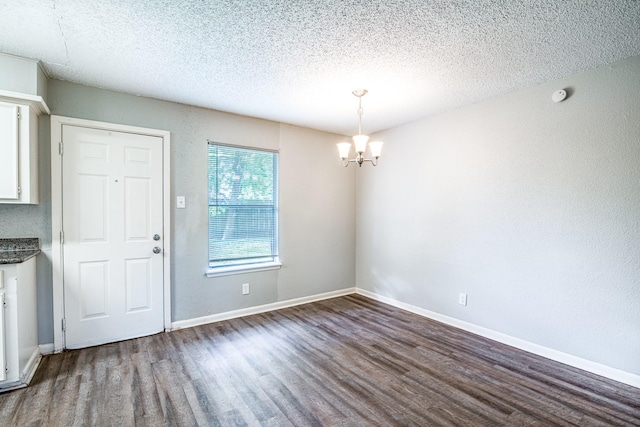 828 Noreda St, Angleton, TX 77515 - unfurnished dining area with dark wood-type flooring, a chandelier, a textured ceiling, and baseboards