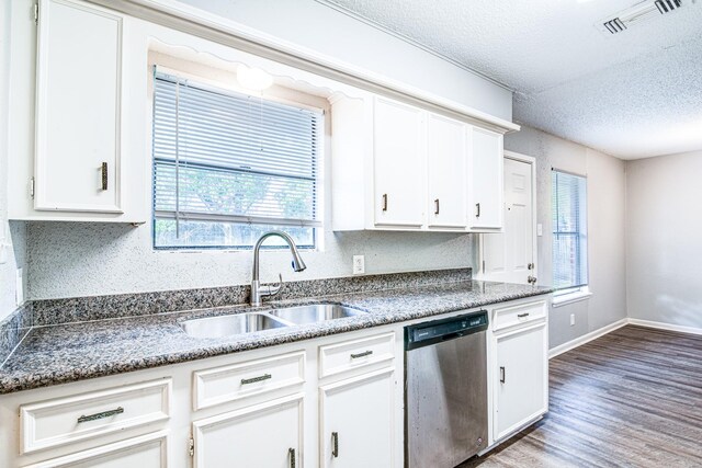 828 Noreda St, Angleton, TX 77515 - kitchen with stainless steel dishwasher, a sink, wood finished floors, a textured ceiling, and white cabinets