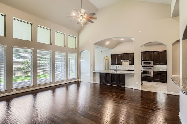2044 Doolan Dr, Conroe, TX 77301 - unfurnished living room featuring a ceiling fan, healthy amount of natural light, light wood-style flooring, high vaulted ceiling, and arched walkways