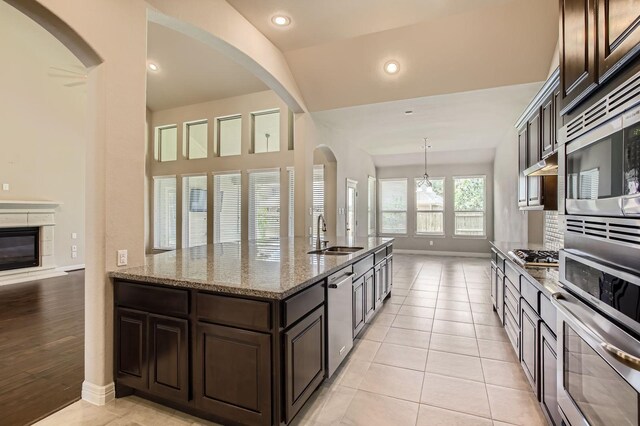 2044 Doolan Dr, Conroe, TX 77301 - kitchen featuring appliances with stainless steel finishes, a sink, baseboards, dark brown cabinets, and light stone counters