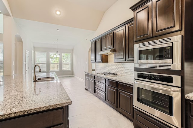 2044 Doolan Dr, Conroe, TX 77301 - kitchen featuring appliances with stainless steel finishes, a sink, arched walkways, backsplash, and light stone counters