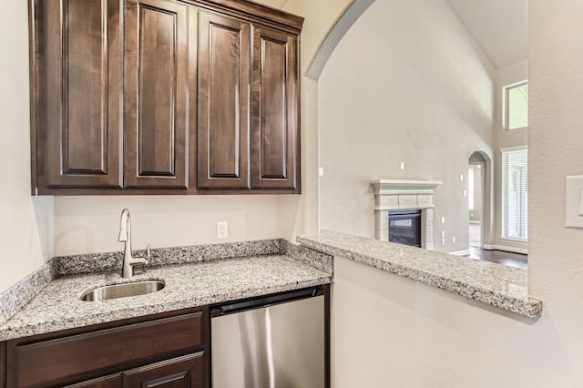 2044 Doolan Dr, Conroe, TX 77301 - kitchen with refrigerator, dark brown cabinets, arched walkways, a sink, and light stone counters