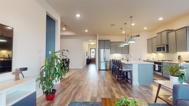 2002 Village Orchard Ln, Katy, TX 77423 - kitchen featuring stainless steel appliances, a breakfast bar, backsplash, gray cabinetry, and a kitchen island