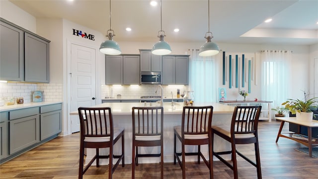 2002 Village Orchard Ln, Katy, TX 77423 - kitchen with stainless steel microwave, gray cabinets, light countertops, recessed lighting, and dark wood finished floors