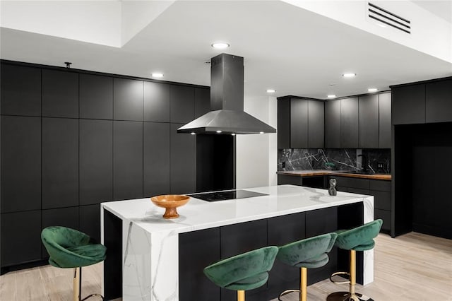 5555 Del Monte Dr Unit 103, Houston, TX 77056 - kitchen featuring island range hood, modern cabinets, black electric stovetop, a kitchen breakfast bar, and recessed lighting