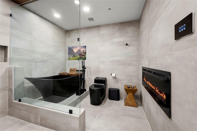 5555 Del Monte Dr Unit 103, Houston, TX 77056 - bathroom with a glass covered fireplace, toilet, tile patterned floors, a shower, and tile walls