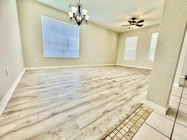 1119 Autumn Green Dr, Missouri City, TX 77459 - unfurnished room with ceiling fan, a chandelier, baseboards, wood finished floors, and a textured wall