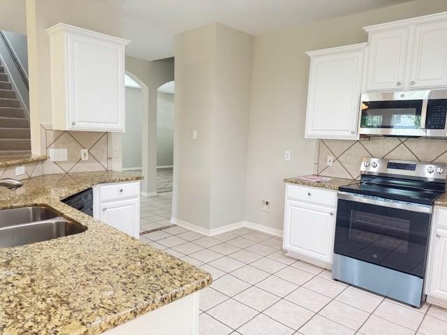 1119 Autumn Green Dr, Missouri City, TX 77459 - kitchen with appliances with stainless steel finishes, light tile patterned floors, arched walkways, and tasteful backsplash