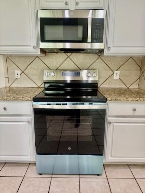 1119 Autumn Green Dr, Missouri City, TX 77459 - kitchen with stainless steel appliances, white cabinets, backsplash, and light tile patterned floors