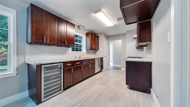 306 W Wilkins St, League City, TX 77573 - kitchen featuring beverage cooler, baseboards, dishwasher, backsplash, and a textured ceiling