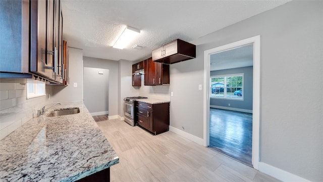 306 W Wilkins St, League City, TX 77573 - kitchen with a sink, high end range, tasteful backsplash, baseboards, and a textured ceiling