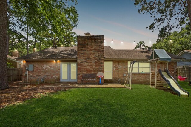 14922 Sandy Creek Dr, Houston, TX 77070 - back of property at dusk featuring french doors, brick siding, a chimney, and a playground