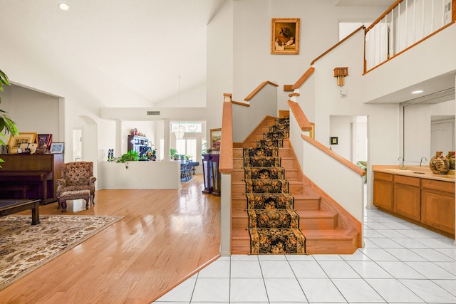 6574 Eagle Ridge Dr, El Paso, TX 79912 - staircase featuring high vaulted ceiling, arched walkways, and wood finished floors