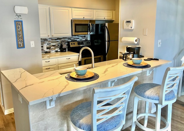 12500 Melville Dr Unit 233D, Montgomery, TX 77356 - kitchen featuring stainless steel appliances, backsplash, light stone countertops, and white cabinetry