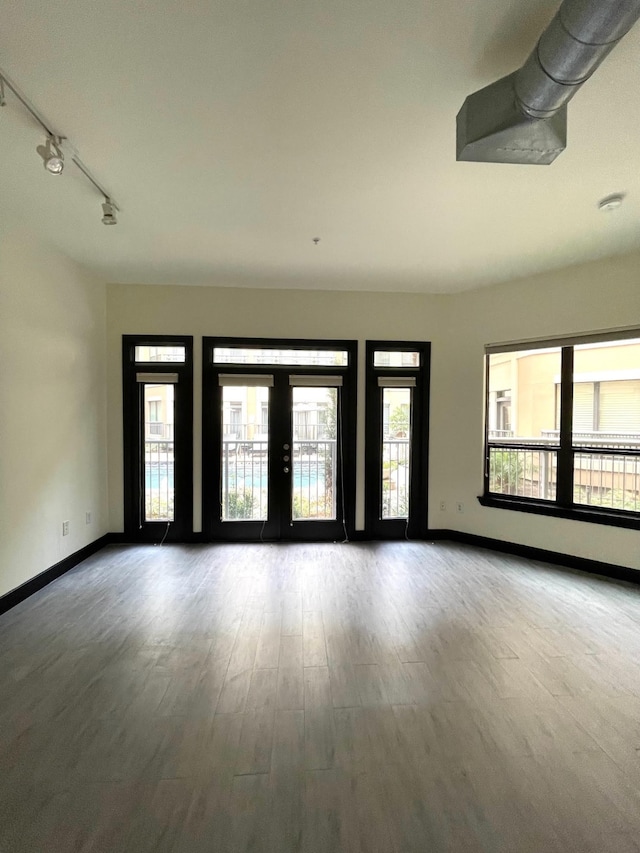 1901 Post Oak Blvd Unit 1213, Houston, TX 77056 - unfurnished room featuring baseboards, wood finished floors, rail lighting, and french doors