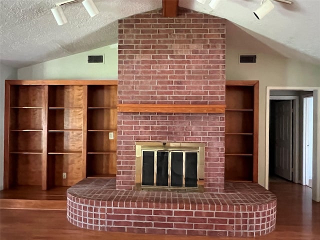 101 Willowbend St, Huntsville, TX 77320 - unfurnished living room with lofted ceiling, wood finished floors, a brick fireplace, and a textured ceiling