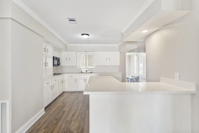 208 Preston St, La Marque, TX 77568 - kitchen featuring black microwave, a sink, a peninsula, tasteful backsplash, and healthy amount of natural light