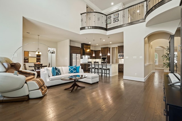 9810 Mount Whitney, Missouri City, TX 77459 - living room featuring dark wood-type flooring, a high ceiling, arched walkways, baseboards, and a chandelier