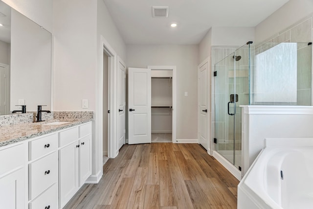 10518 Sutter Creek Dr, Iowa Colony, TX 77583 - bathroom with a stall shower, vanity, a garden tub, wood finished floors, and recessed lighting