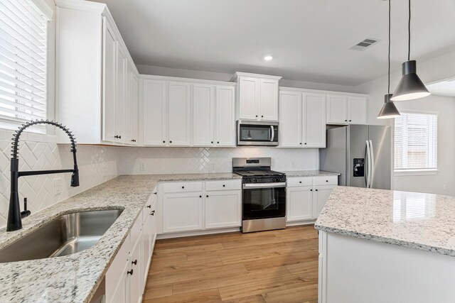 10518 Sutter Creek Dr, Iowa Colony, TX 77583 - kitchen with appliances with stainless steel finishes, a sink, white cabinets, light wood finished floors, and recessed lighting
