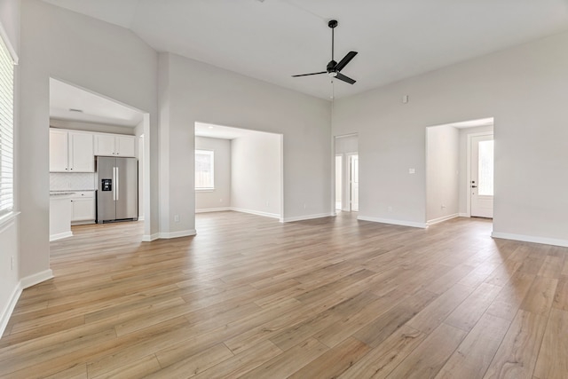 10518 Sutter Creek Dr, Iowa Colony, TX 77583 - unfurnished living room with ceiling fan, light wood finished floors, baseboards, and a high ceiling