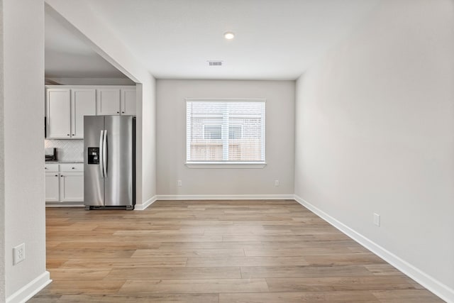 10518 Sutter Creek Dr, Iowa Colony, TX 77583 - kitchen with stainless steel refrigerator with ice dispenser, white cabinets, light wood finished floors, and tasteful backsplash