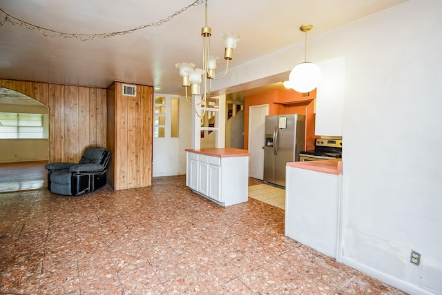 8602 Ariel St, Houston, TX 77074 - kitchen with stainless steel appliances, butcher block counters, white cabinets, hanging light fixtures, and wooden walls