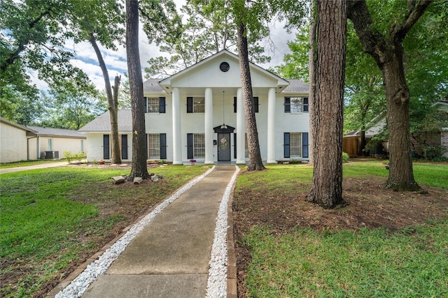 215 Whispering Oaks Dr, Taylor Lake Village, TX 77586 - greek revival house with central AC unit, a front yard, stucco siding, and a shingled roof