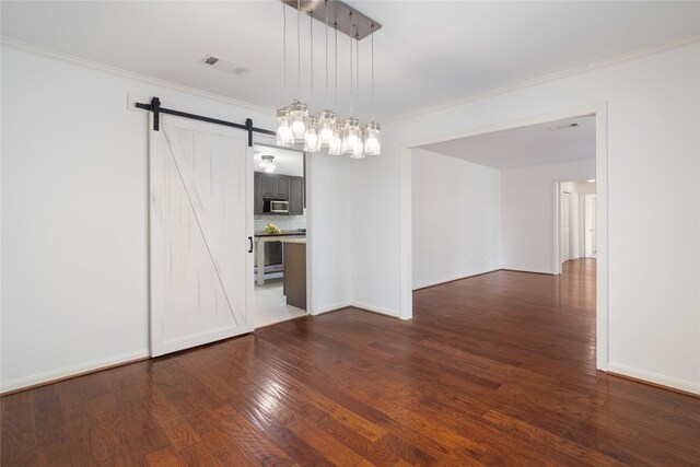215 Whispering Oaks Dr, Taylor Lake Village, TX 77586 - spare room with a barn door, ornamental molding, dark wood-style flooring, and baseboards