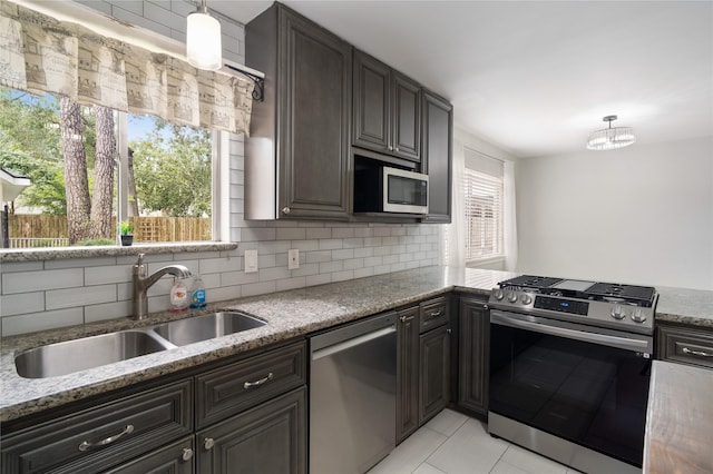 215 Whispering Oaks Dr, Taylor Lake Village, TX 77586 - kitchen featuring appliances with stainless steel finishes, a sink, decorative backsplash, light tile patterned flooring, and light stone counters