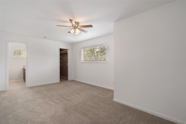 215 Whispering Oaks Dr, Taylor Lake Village, TX 77586 - unfurnished bedroom featuring light carpet, baseboards, a walk in closet, and ceiling fan
