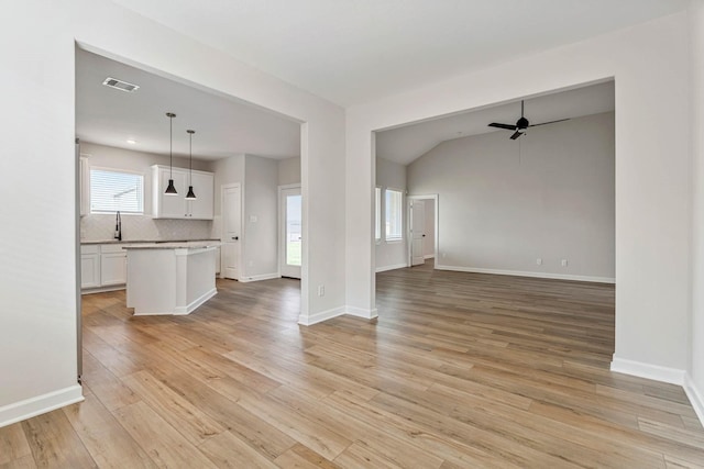 1927 June Lake Ln, Iowa Colony, TX 77583 - unfurnished living room featuring ceiling fan, a sink, light wood finished floors, baseboards, and vaulted ceiling