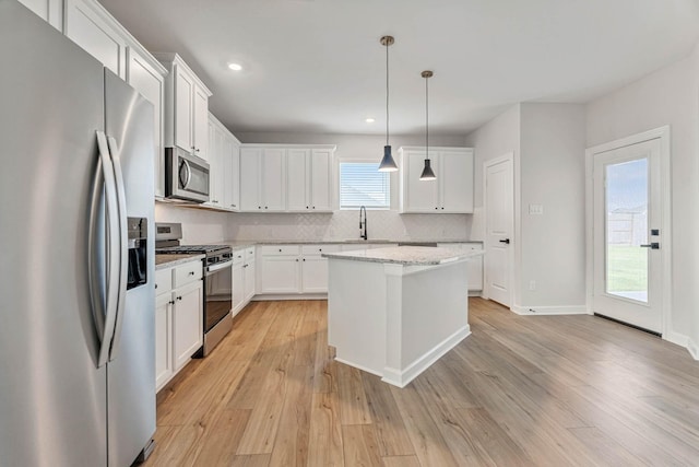 1927 June Lake Ln, Iowa Colony, TX 77583 - kitchen featuring stainless steel appliances, backsplash, a sink, light wood-type flooring, and a center island
