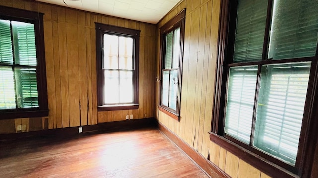 614 18th St, Galveston, TX 77550 - unfurnished room featuring wooden walls, light wood-type flooring, healthy amount of natural light, and baseboards