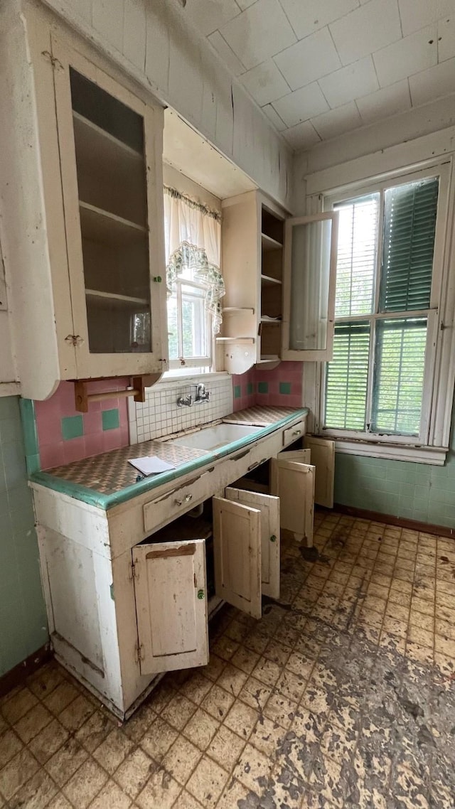 614 18th St, Galveston, TX 77550 - kitchen with tile countertops, open shelves, a sink, backsplash, and light flooring