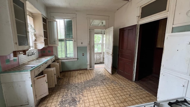 614 18th St, Galveston, TX 77550 - kitchen with a sink, decorative backsplash, light flooring, and open shelves