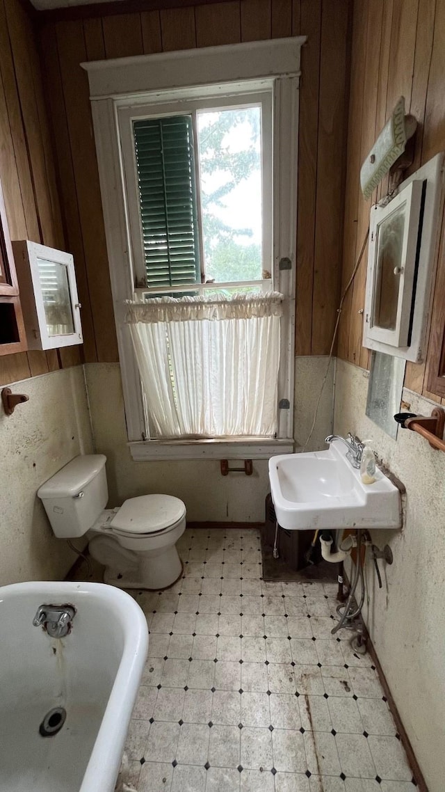 614 18th St, Galveston, TX 77550 - full bathroom featuring a freestanding bath, tile patterned floors, a sink, toilet, and wooden walls