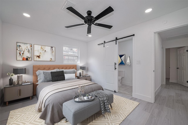 15622 Corsair Rd, Houston, TX 77053 - bedroom featuring a barn door, light wood-type flooring, recessed lighting, ensuite bath, and a ceiling fan