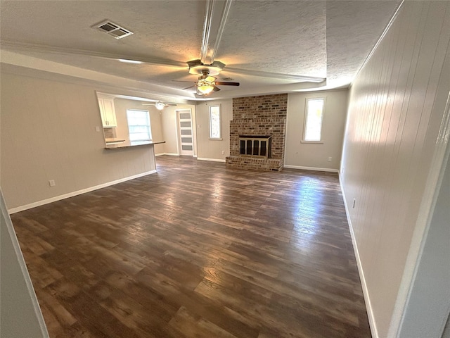 203 Ridgewood Dr, Spring, TX 77386 - unfurnished living room with a textured ceiling, dark wood finished floors, plenty of natural light, a ceiling fan, and a fireplace