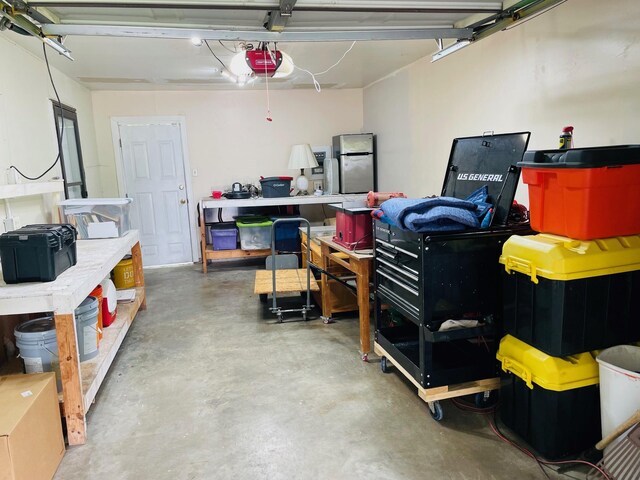 7635 Nordling Rd, Houston, TX 77037 - garage featuring a garage door opener, a workshop area, and freestanding refrigerator