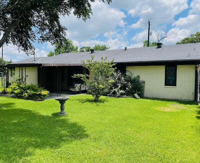 7635 Nordling Rd, Houston, TX 77037 - back of property with brick siding, a lawn, a patio area, and roof with shingles