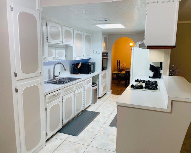 7635 Nordling Rd, Houston, TX 77037 - kitchen with a sink, black appliances, arched walkways, light countertops, and light tile patterned flooring