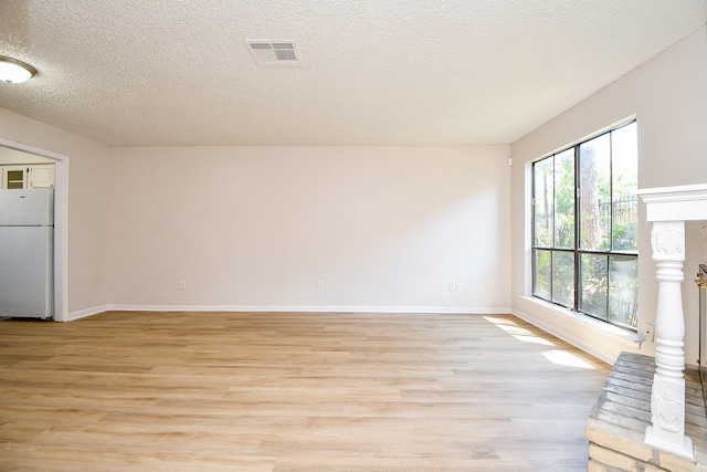 5001 Lamonte Ln Unit 14, Houston, TX 77092 - unfurnished living room with a fireplace with raised hearth, light wood finished floors, baseboards, and a textured ceiling