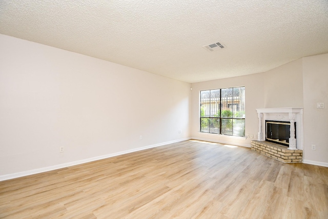 5001 Lamonte Ln Unit 14, Houston, TX 77092 - unfurnished living room with light wood-type flooring, baseboards, a fireplace, and a textured ceiling