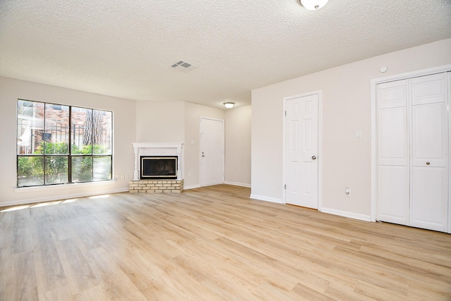 5001 Lamonte Ln Unit 14, Houston, TX 77092 - unfurnished living room featuring light wood-style floors, a textured ceiling, baseboards, and a fireplace