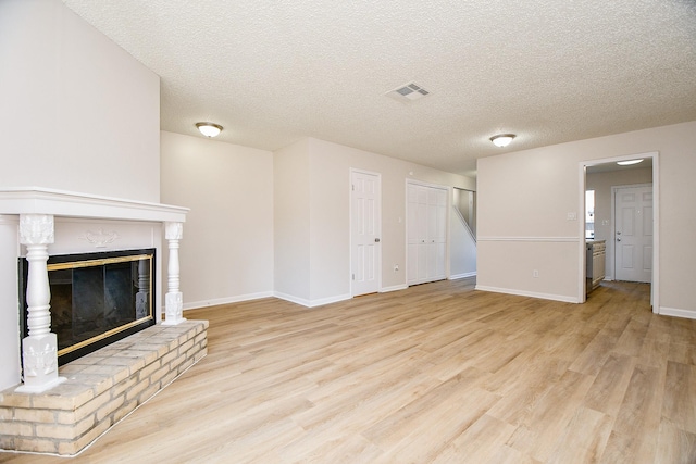 5001 Lamonte Ln Unit 14, Houston, TX 77092 - unfurnished living room with light wood-style floors, baseboards, a glass covered fireplace, and a textured ceiling